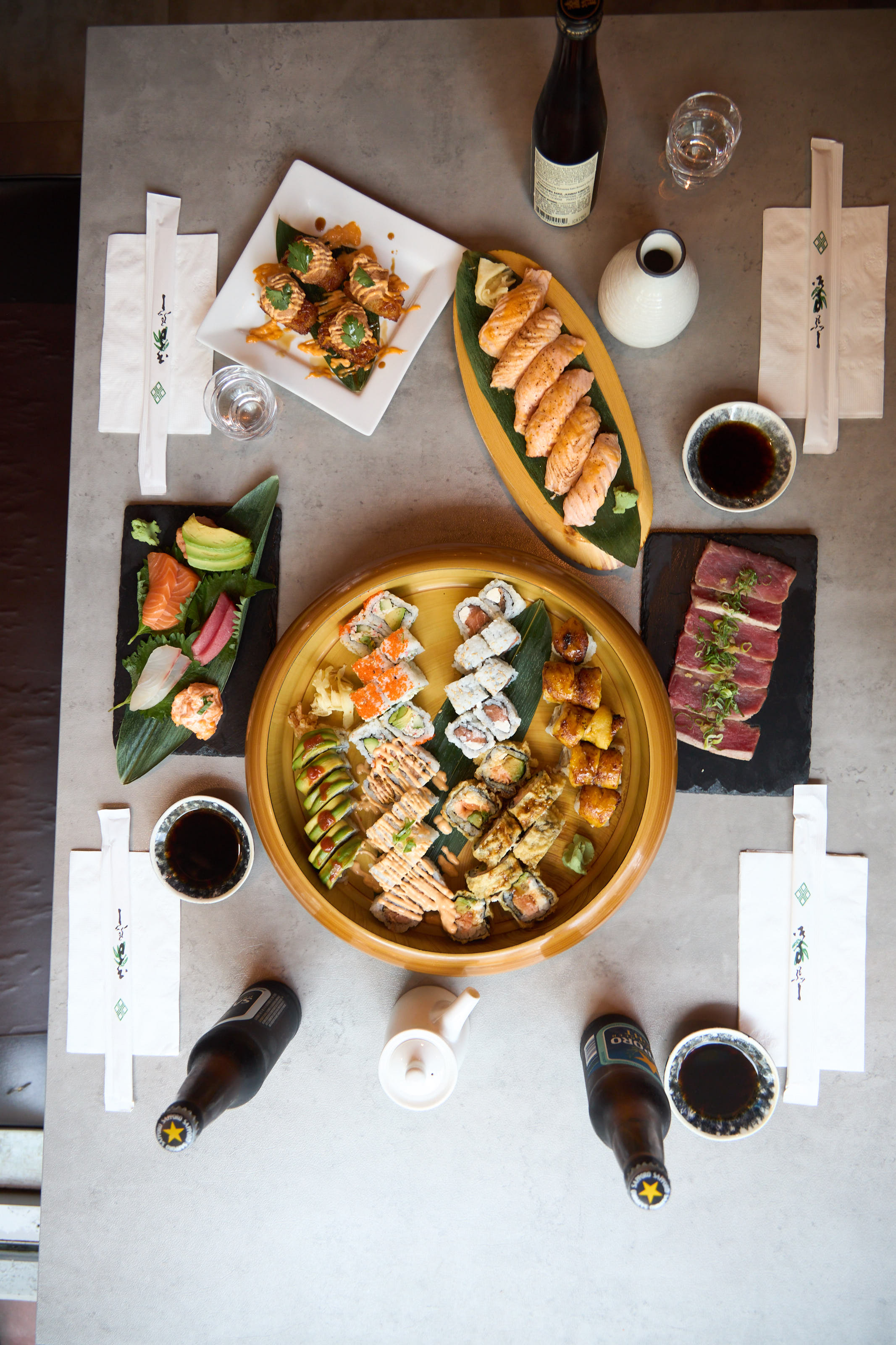 Aerial view of dining table with gold bowl of rolls, sashimi, and nigiri platters
