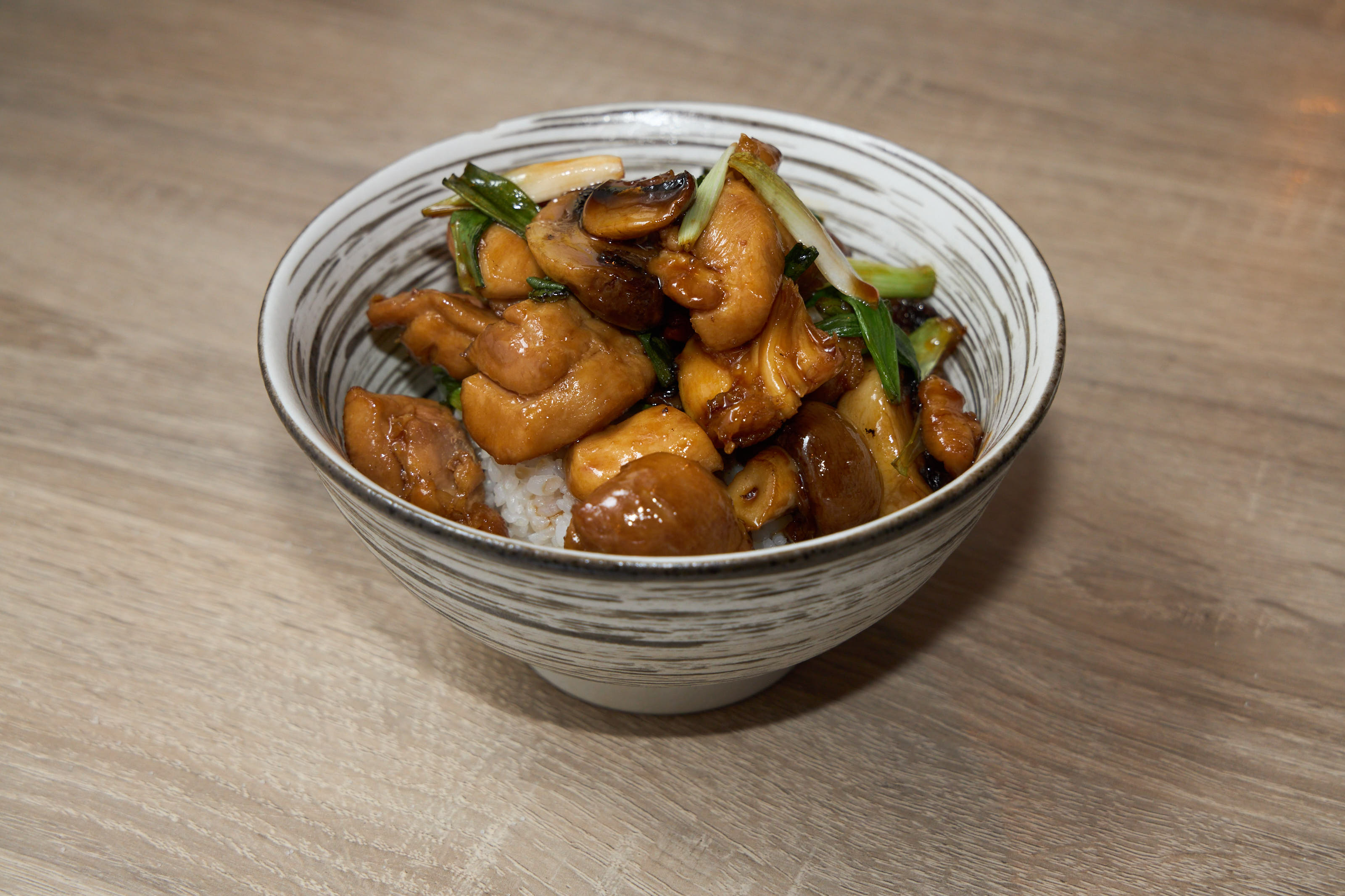 Chicken teriyaki rice bowl with mushrooms and bok choy in glazed ceramic bowl