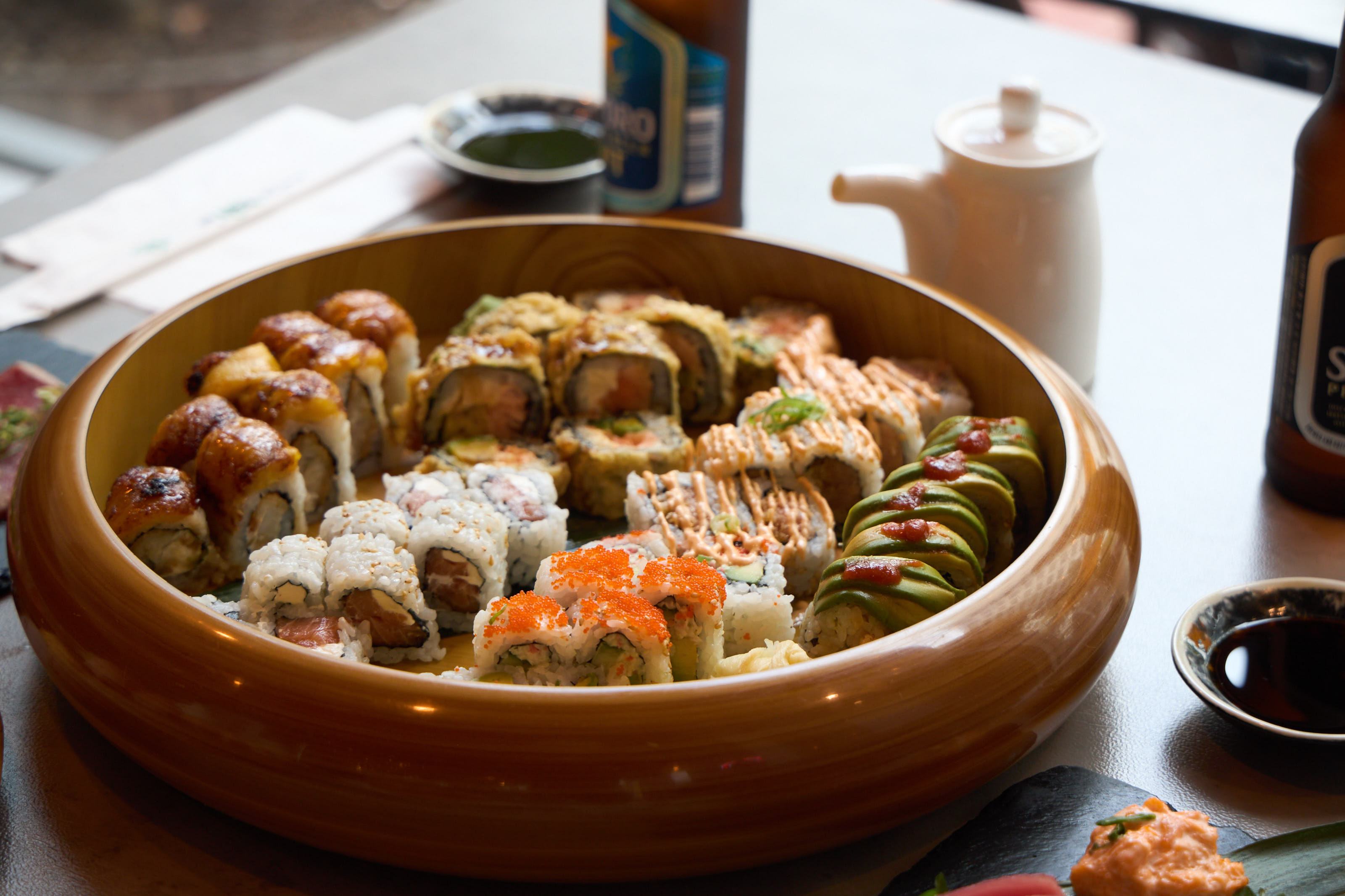 Assorted rolls including dragon, mango, and spicy rolls in a wooden bowl