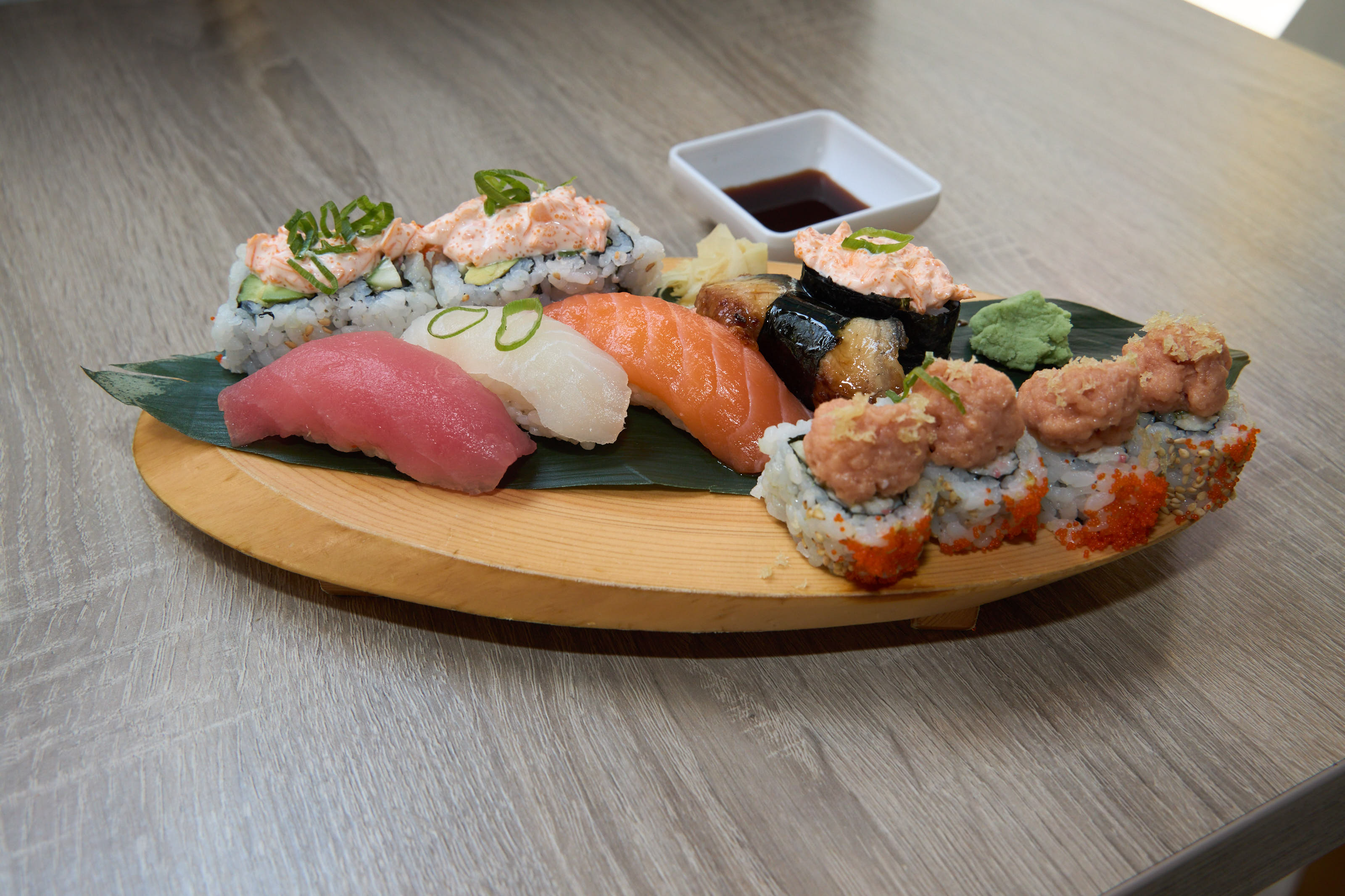 Assorted nigiri including tuna, salmon, and white fish on wooden oval boat
