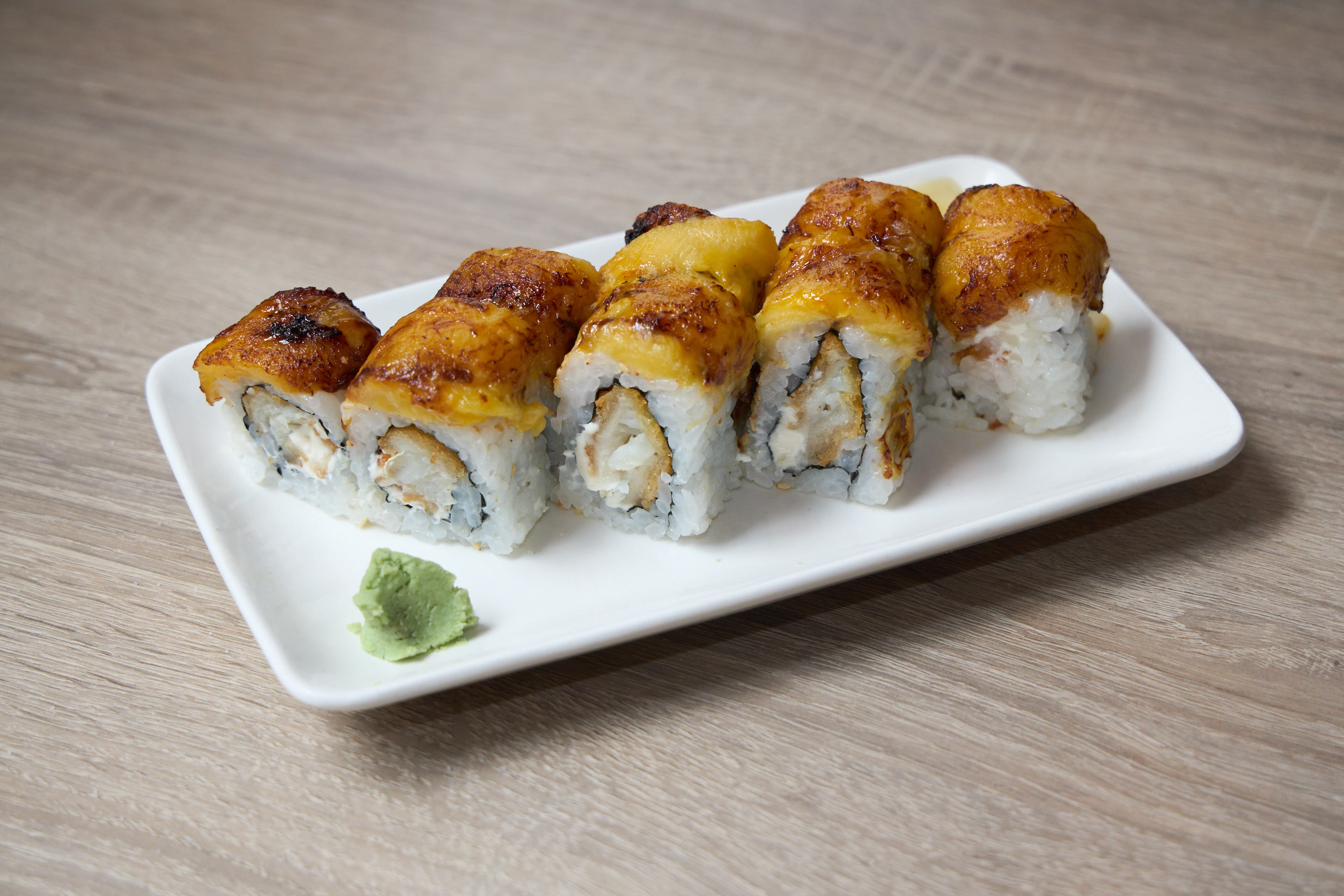Baked roll with golden crust and wasabi on white plate