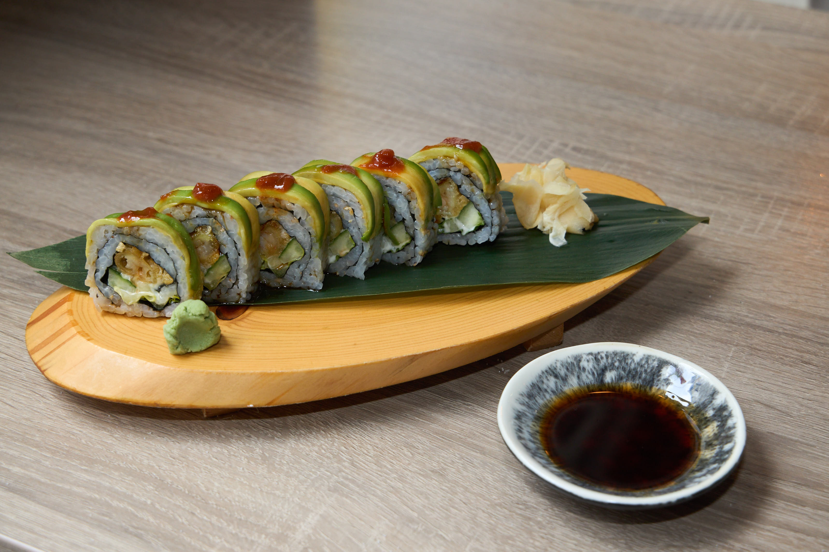 Dragon Roll with avocado and sweet sauce on a wood board