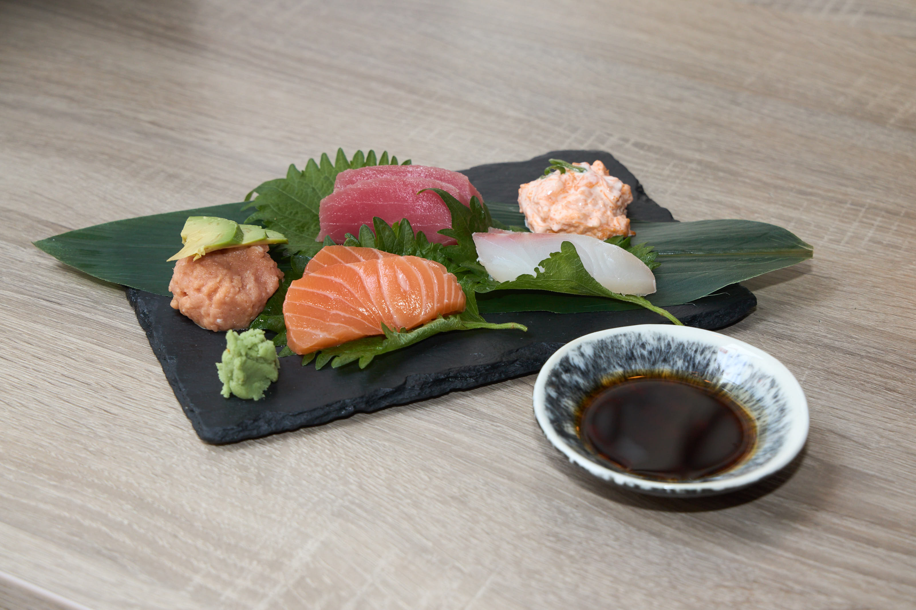 Sashimi platter with tuna, salmon, and white fish on slate board with wasabi and soy sauce