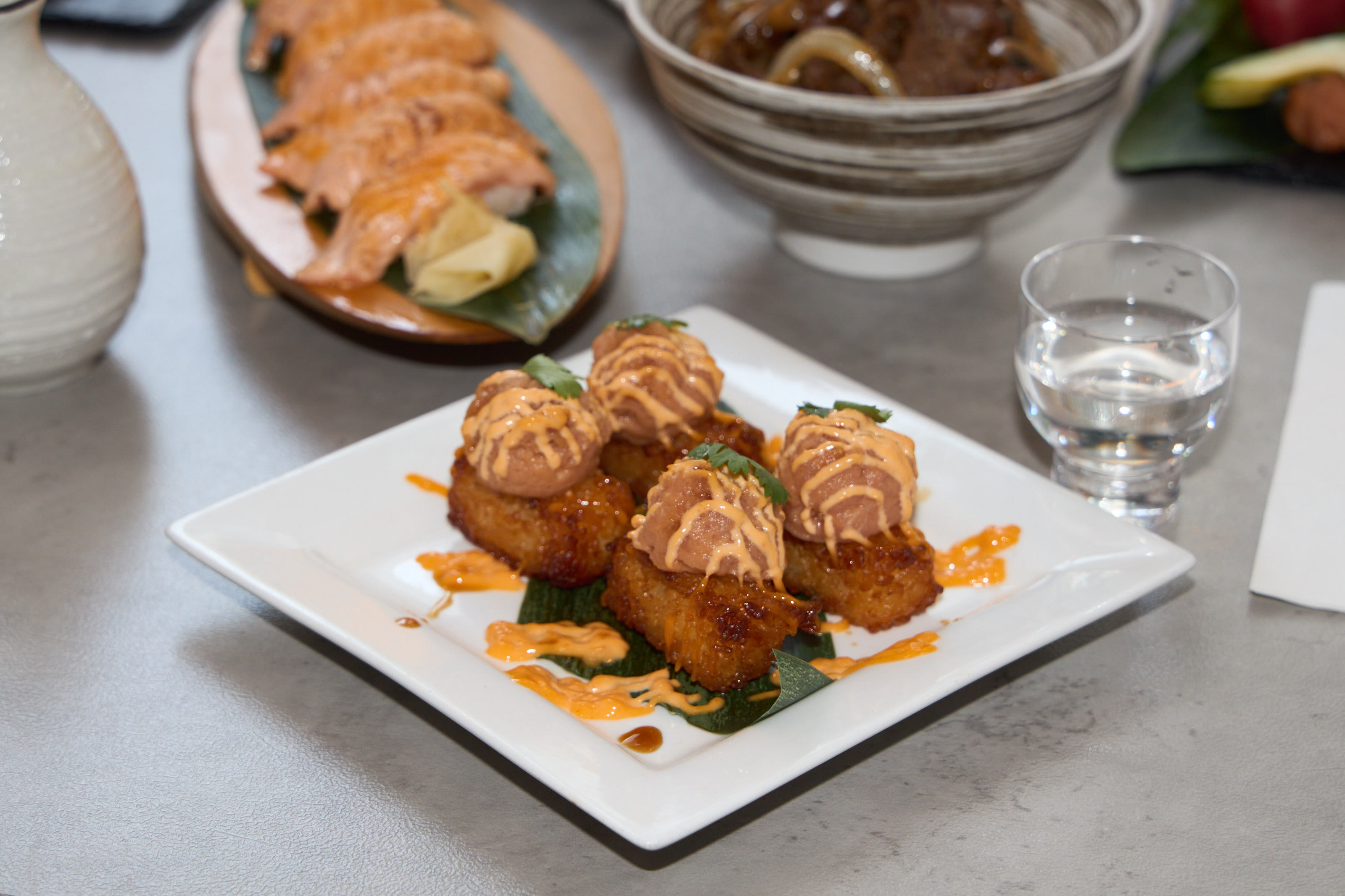 Spicy crispy bites with salmon nigiri in background