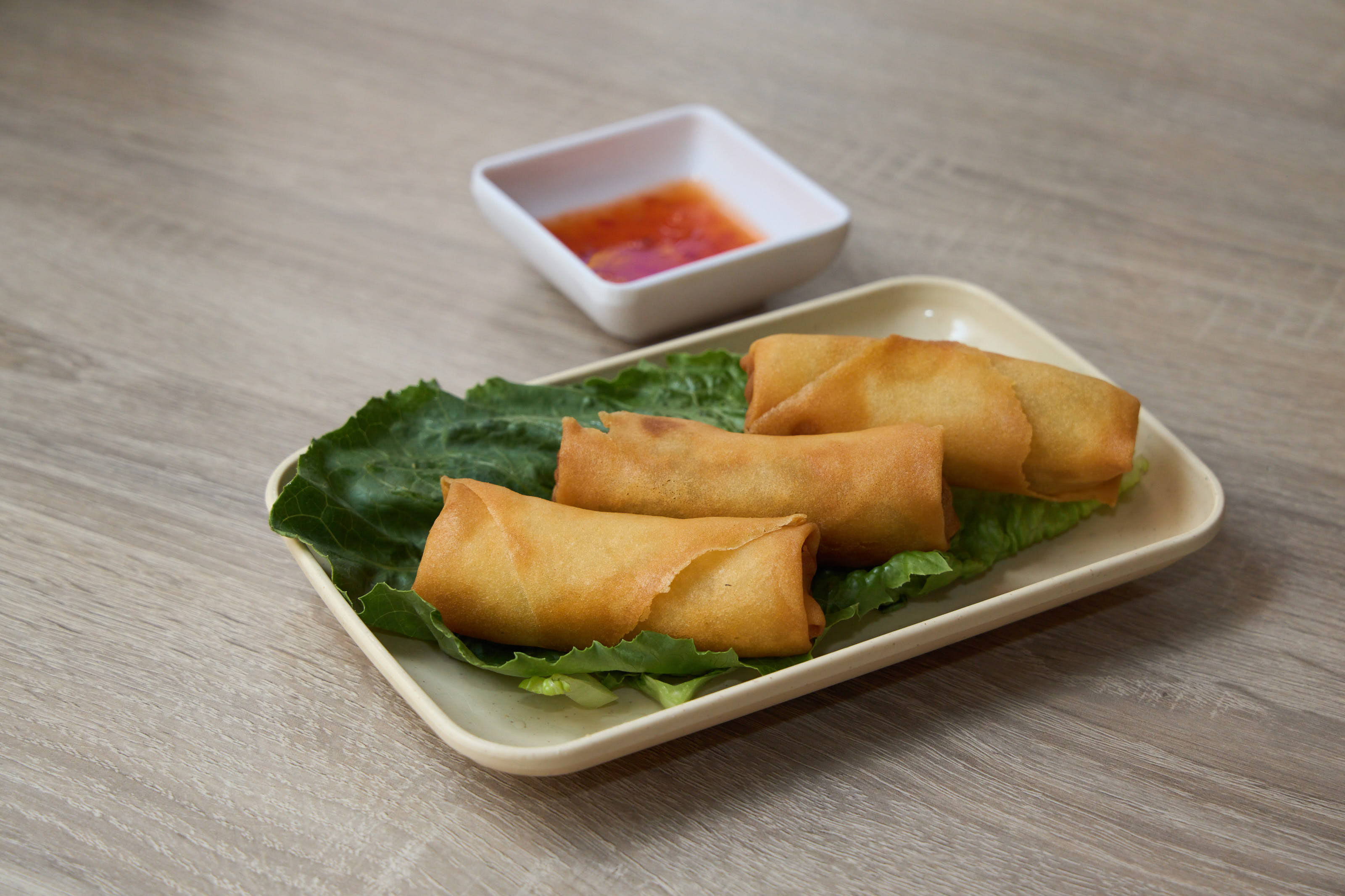 Crispy spring rolls on lettuce with sweet chili dipping sauce