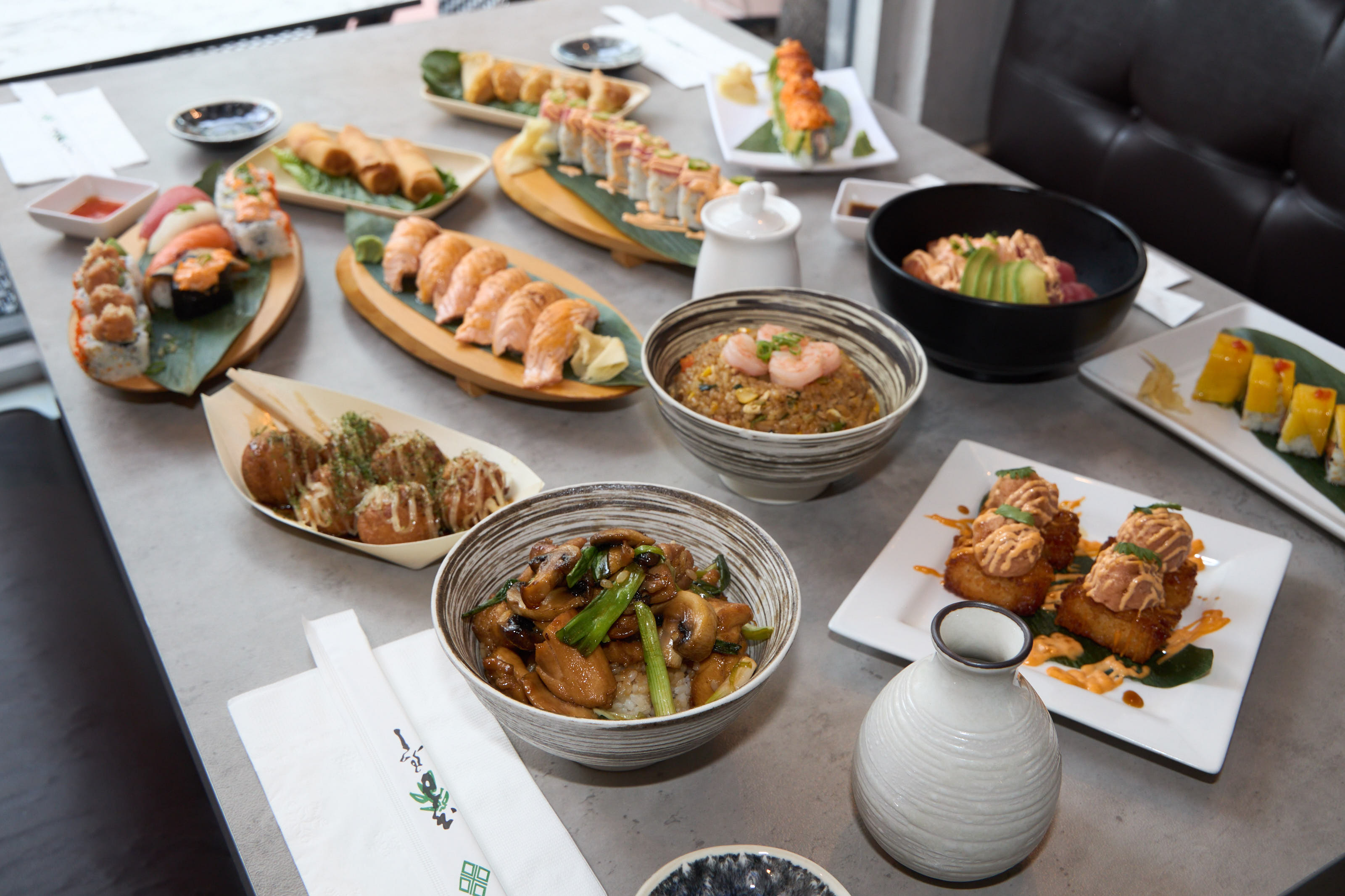 Full table spread with rolls, nigiri, poke bowls, and more
