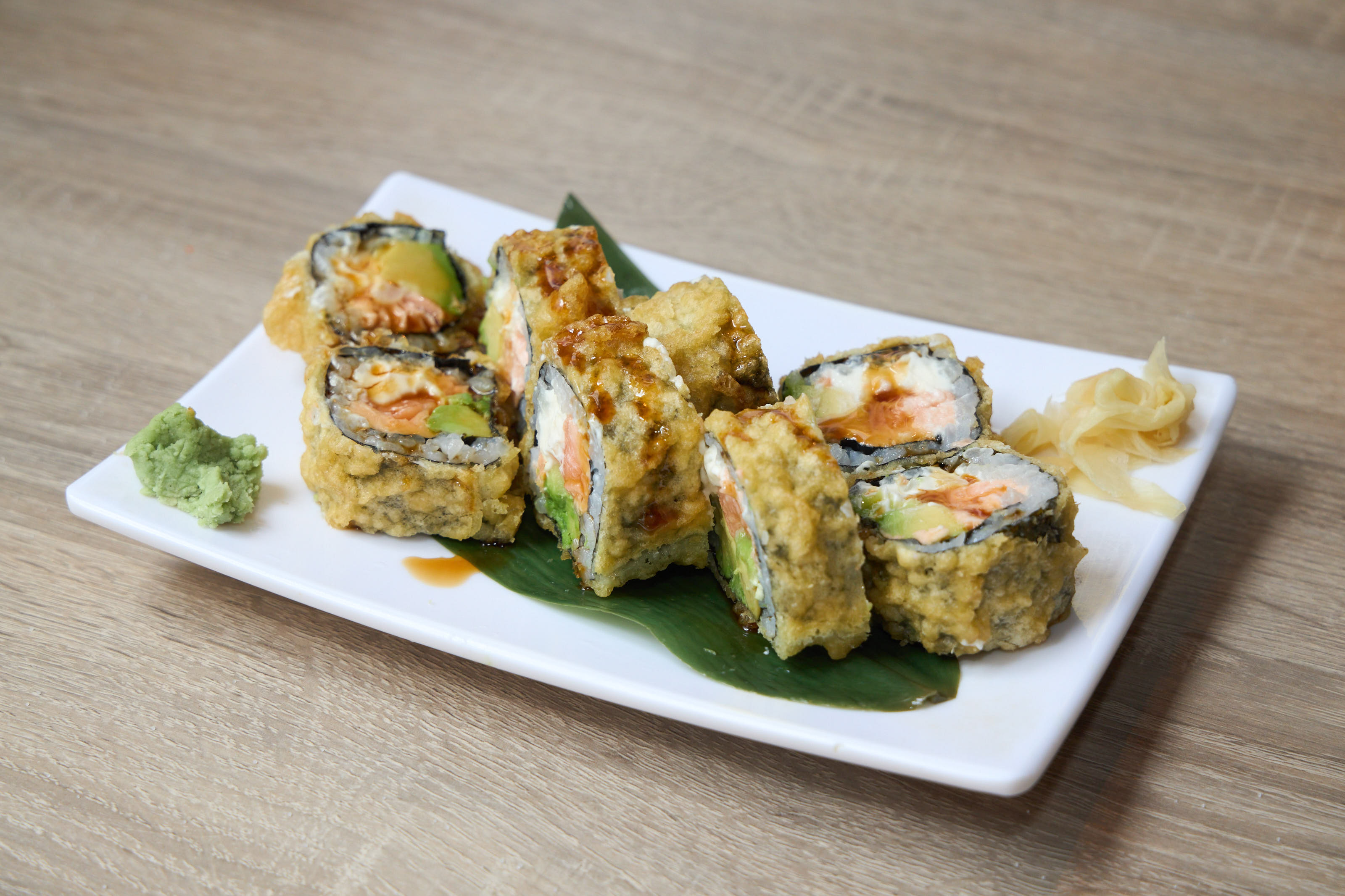 Tempura roll with avocado and spicy sauce on banana leaf