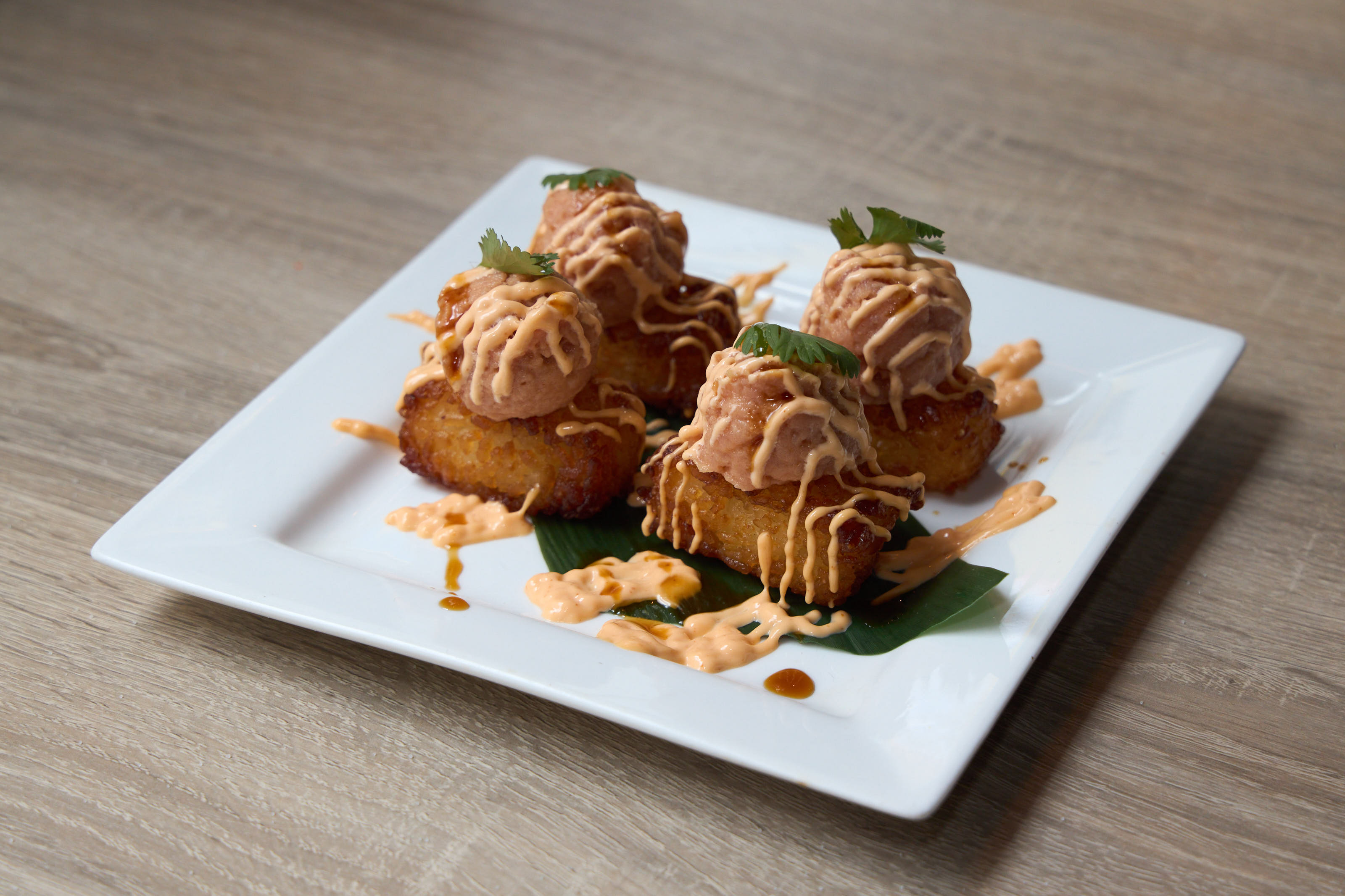 Crispy fried tostones topped with spicy tuna and spicy mayo on banana leaf