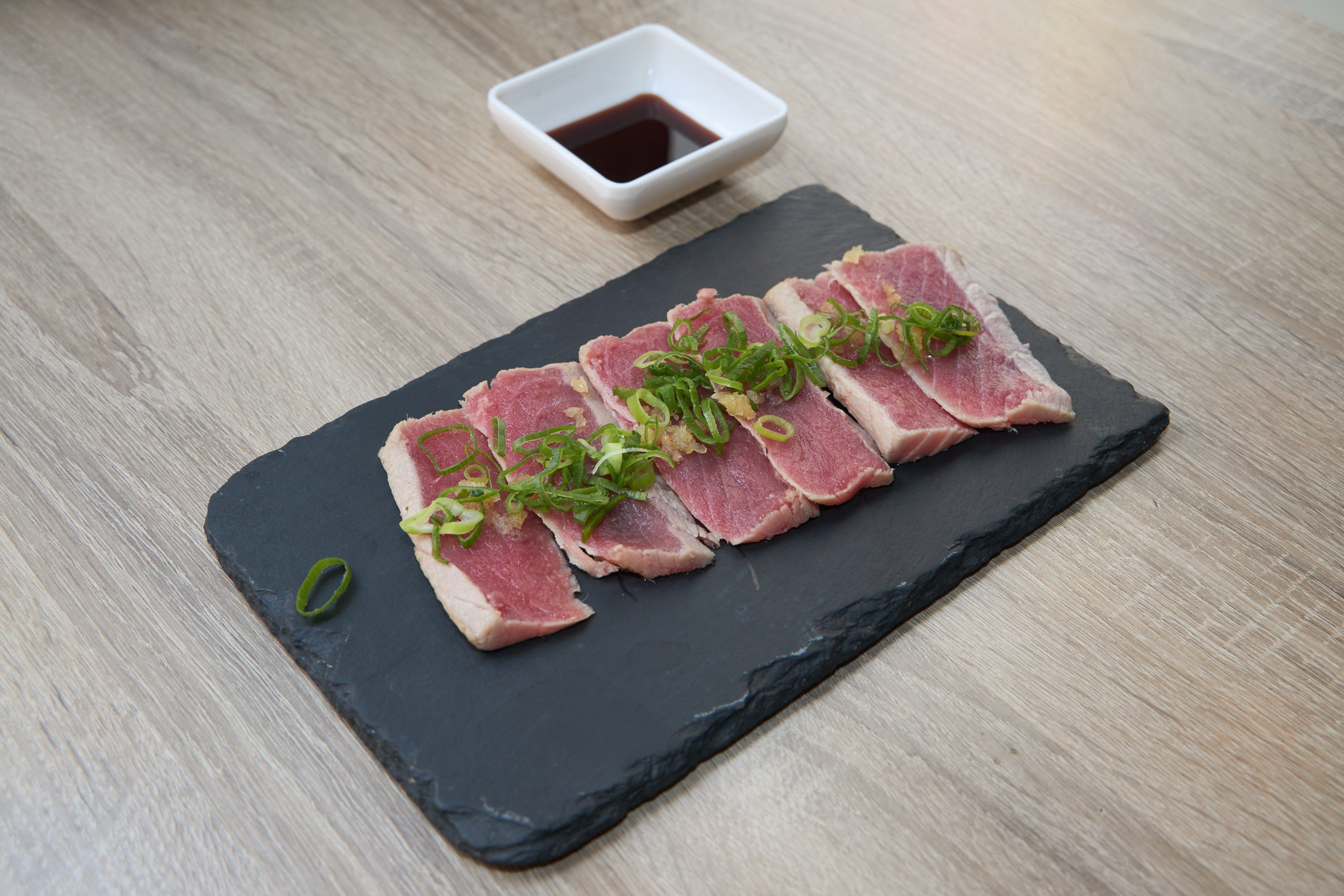 Tuna tataki on slate with scallions and ponzu